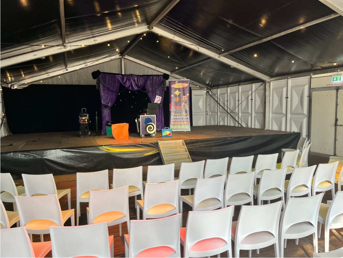 Het podium van Lange Jan in een feesttent met rijen stoelen